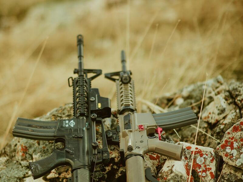 Two custom rifles on rocky terrain